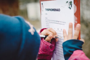 bilden visar ett barn som skriver på ett tipspormenad på Skansen